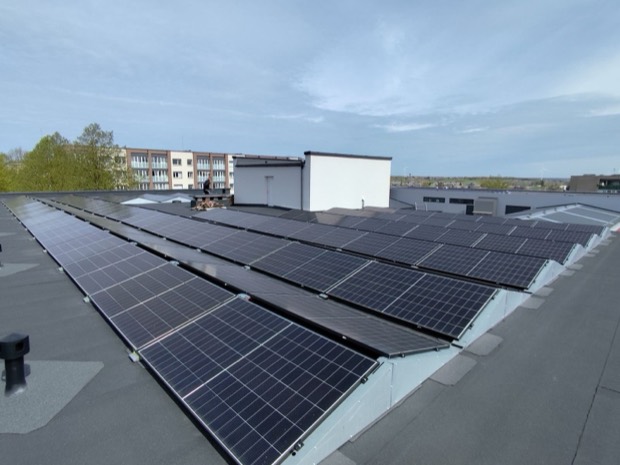 Saulės elektrinė ant plokščio pastato stogo mieste